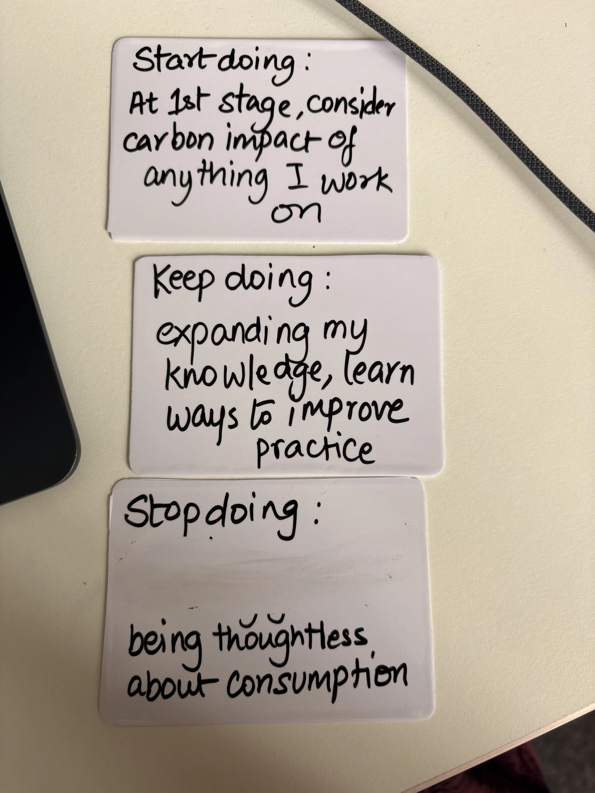 Three mini playcard sized whiteboards on a table with messages written in erasable pen.
