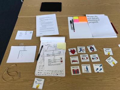 Interview kit on a table, with do not disturb sign, pens, post-its, and a card sorting exercise'